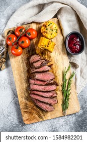 Sliced Grilled Filet Mignon Steak On A Wooden Chopping Board. Beef Tenderloin. Gray Background. Top View