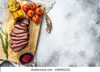 Sliced Grilled Filet Mignon Steak On A Wooden Chopping Board. Beef Tenderloin. Gray Background. Top View. Space For Text