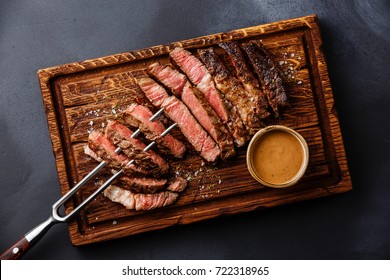 Sliced grilled meat steak Rib eye on meat fork and Pepper sauce on dark background