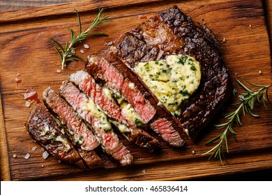 Sliced grilled Medium rare barbecue steak Ribeye with herb butter on cutting board close up - Shutterstock ID 465836414