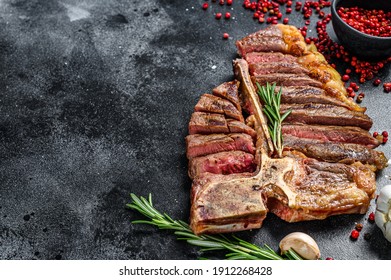 Sliced Grilled T-bone Steak. Cooked Tbone Beef Meat. Black Background. Top View. Copy Space