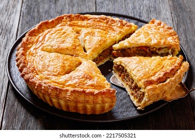 sliced Ground Beef Meat Pie with a flaky puff pastry double crust with hearty minced beef cooked with vegetables and seasoning on black plate on wood table - Shutterstock ID 2217505321