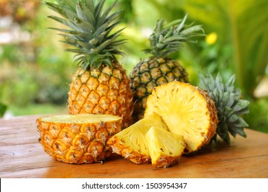 Sliced and half of Pineapple(Ananas comosus) on wooden table with blurred garden background.Sweet,sour and juicy taste.Have a lot of fiber,vitamins C and minerals.Fruits or healthcare concept. - Shutterstock ID 1503954347