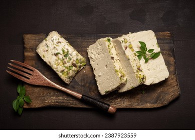 Sliced ​​turkish halva with pistachio on a wooden plate and rustic background. Traditional oriental dessert