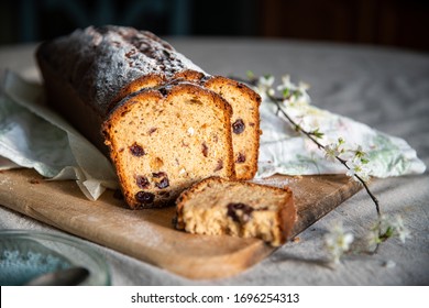 Sliced Homemade Traditional Pound Cake With Dried Fruits And Cranberries On Wooden Board With Blooming Cherry Twig.