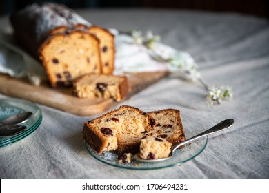 Sliced Homemade Traditional Pound Cake With Dried Fruits And Cranberries On Wooden Board And Glass Plate With Slice Of Cake With Blooming Cherry Twigs On Linen Tablecloth.