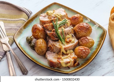 Sliced honey mustard roast pork tenderloin with baby potatoes and caperberry garnish - Powered by Shutterstock