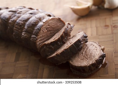 Sliced juicy beef tenderloin on wooden plate