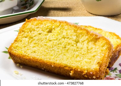 Sliced Lemon Drizzle Cake On A Plate With Cup Of Tea And A Milk Jug In The Background