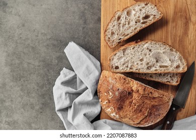 Sliced loaf of artisan sourdough bread on a cutting board on a gray concrete table. Top view with copy space. - Powered by Shutterstock