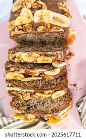 Sliced Loaf Of Banana Nut Bread Drizzled Homemade Caramel On A Pink Cutting Board.