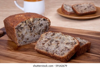 Sliced Loaf Of Banana Walnut Bread On A Cutting Board With One Serving Of Two Slices And A Mug In The Background