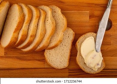 A sliced loaf of wheat bread and a sandwich with melted cheese on a wooden cutting Board. Close up.