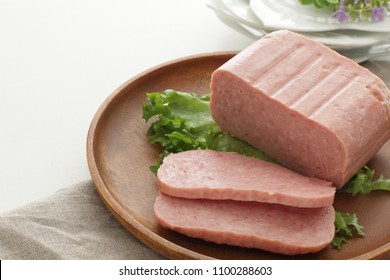 Sliced luncheon meat on wooden plate