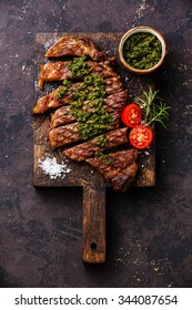 Sliced medium rare grilled beef barbecue Sirloin steak with chimichurri sauce on cutting board on dark background