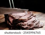 Sliced medium-rare roast beef on a wooden cutting board, with a knife mid-slice, showcasing juicy, tender, and perfectly cooked meat.