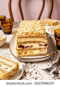 Sliced Moskva cake on a rustic table, famous Moskva hotel from Belgrade signature dessert with buttery cream layers filled with cherries and pineapple pieces tossed with almond flakes