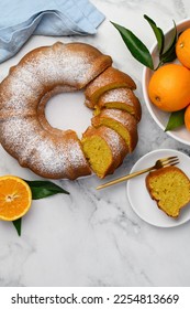 Sliced orange bundt cake dusted with powdered sugar. Fruity citrus dessert. Copy space. Top view - Shutterstock ID 2254813669