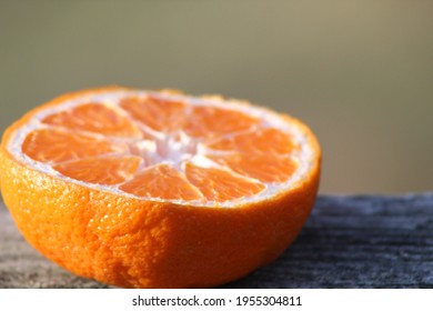 A Sliced Orange Sitting On A Rustic Deck, Waiting For A Bird To Come Along And Eat It. 