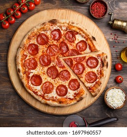 Sliced Oven Baked Pepperoni Pizza Over Wooden Background With Ingredients For Cooking. Overhead View