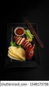 Sliced Peking Duck With Pancakes On A Plate On A Black Background