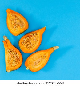 Sliced Pieces Of Organic Pumpkin On Cyan Or Blue Background. Minimal Autumn Food Layout. Flat Lay