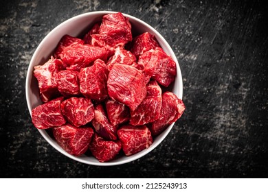 Sliced pieces of raw beef in a bowl. On a black background. High quality photo - Shutterstock ID 2125243913