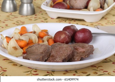 Sliced Pot Roast With Carrots, Onions, And Potatoes On A Dinner Plate