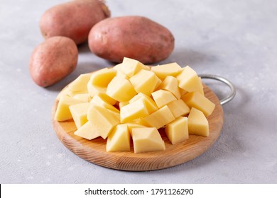 Sliced potato on a cutting board on a light concrete background. Preparing potatoes for cooking.