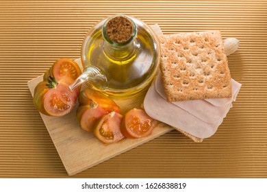 Sliced Raf Tomato, Next To An Oil Porch And A Sandwich Of Meatloaf On Whole Wheat Bread, All Placed On A Wooden Board