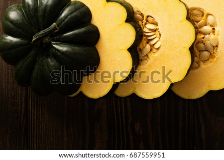 Sliced raw acorn squash on dark background overhead shot
