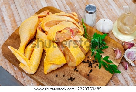 Sliced raw chicken, garlic, fresh parsley and spices on wooden cutting board