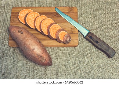 Sliced raw sweet potatoes on a wooden cutting board and jute backgroud. Product photo of batats. Healthy diet for vegetarians and vegans. Source of vitamins. Wooden plank with batatas and knife - Shutterstock ID 1420660562
