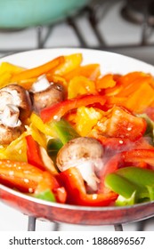 Sliced Red, Yellow, Orange, And Green Bell Peppers And Whole Portabella Mushrooms In A Frying Pan