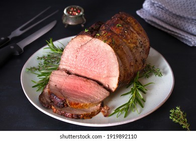 Sliced roast beef with herbs on plate. Horizontal photo