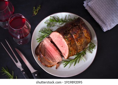 Sliced Roast Beef With Herbs And Red Wine On Dark Background. Overhead Horizontal Photo