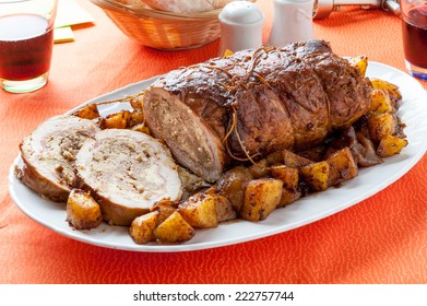 Sliced Roasted And Stuffed Meatloaf With A Side Of Baked Potatoes