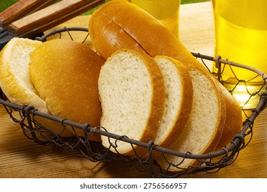Sliced round bread in rustic wire basket with olive oil, golden crusty artisan bread close-up
