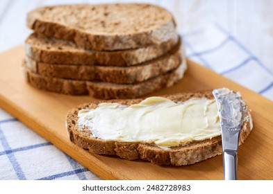 Sliced rye bread with butter on a white wooden table, selective focus. - Powered by Shutterstock