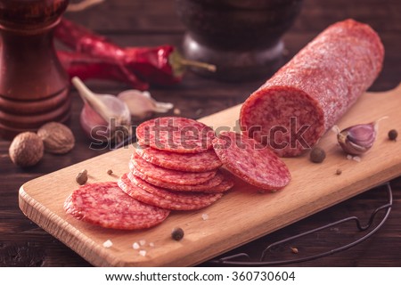 Sliced salami on cutting board.Toned