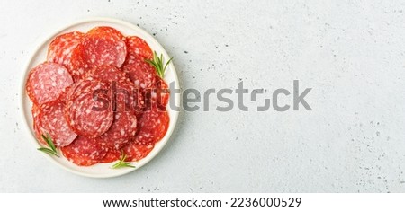 Sliced salami sausage on a plate over white background with space for text