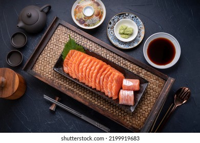 Sliced ​​Fresh Salmon black plate on wooden background, Salmon sashimi salmon sashimi with sauce and wasabi on black background.
