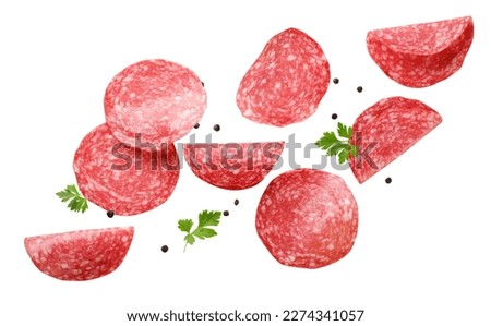 Sliced sausage with parsley leaves and peppercorns are flying on a white background. Isolated