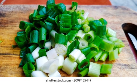 sliced scallions on a wooden cutting board, looks fresh and ready to add flavor to the dish