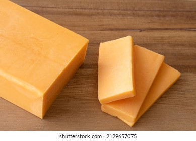 Sliced Sharp Cheddar Cheese On A Cutting Board