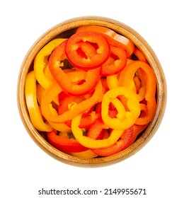 Sliced snacking mini sweet peppers, in a wooden bowl. Cross sections of ripe and fresh bell peppers, also called capsicums. Fruits of Capsicum annuum cultivars. Close-up from above, macro food photo.