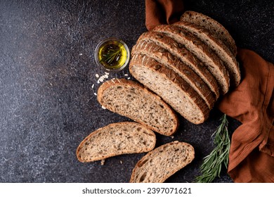 Sliced sourdough bread from whole grain flour and pumpkin seeds on a grid, olive oil and black olive on a rustic wooden table. Artisan bread. - Powered by Shutterstock