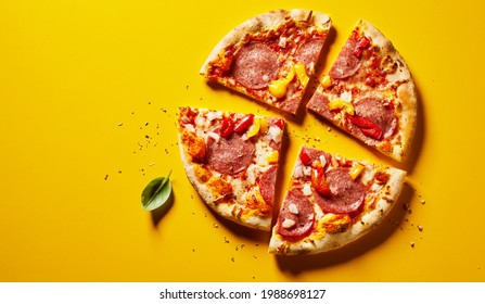 Sliced Spicy Seasoned Salami Or Pepperoni Pizza With Peppers On Yellow With Copyspace Viewed As A Flat Lay From Above