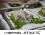 Sliced squid on lettuce leaf in white plate on wooden table