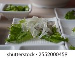 Sliced squid on lettuce leaf in white plate on wooden table